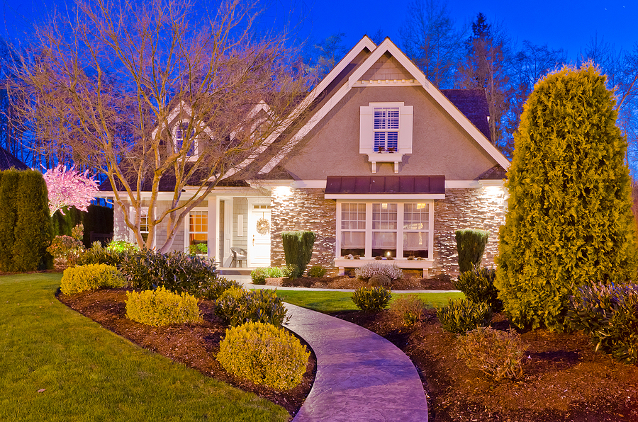 Two story home with new landscape lighting at dusk.