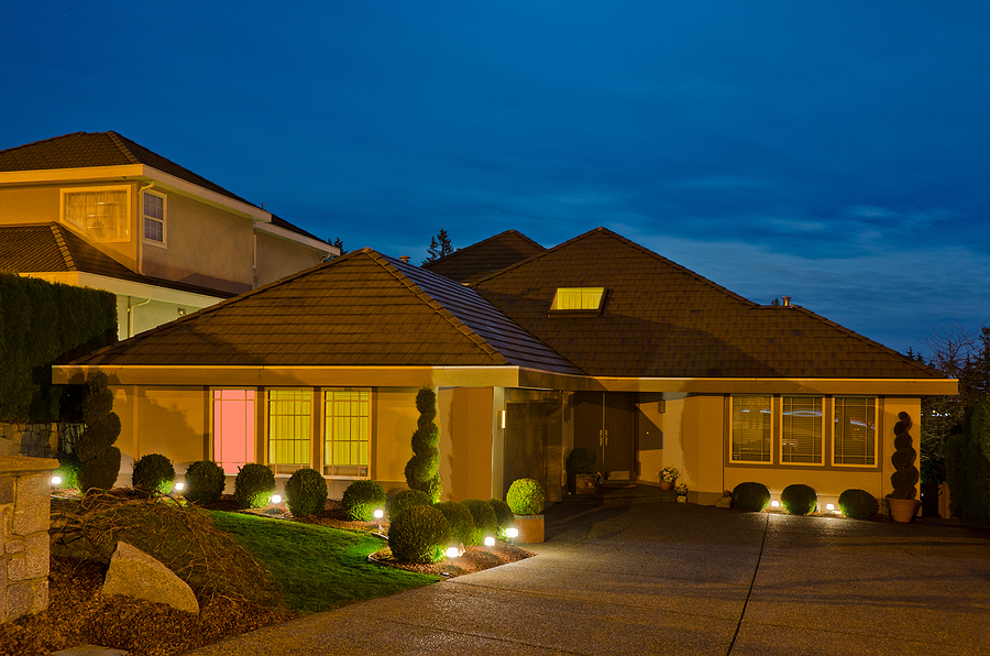 Large home in nice neighborhood at night with landscape lighting adding curb appeal.