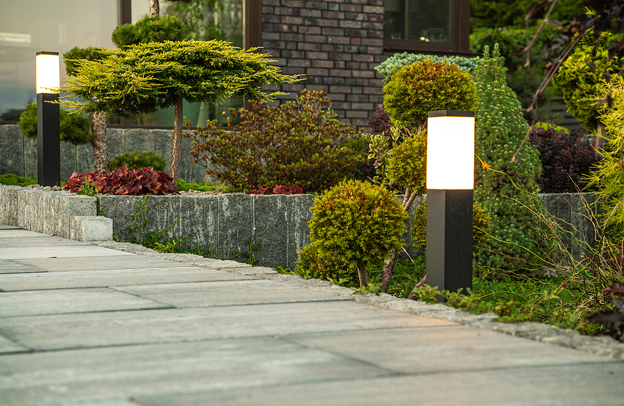 Concrete walkway with post lights and plants along the sides.