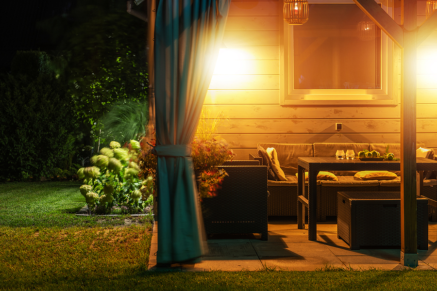 well-lit back yard patio with furniture and landscape lighting